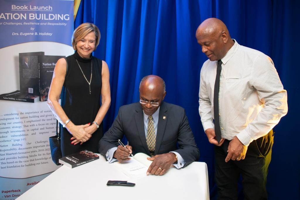 drs. Eugene B. Holiday autographing a copy of Nation Building for Leroy (Beau Beau) Brooks and Ann Marie Brooks during the book launch on December 13, 2023.